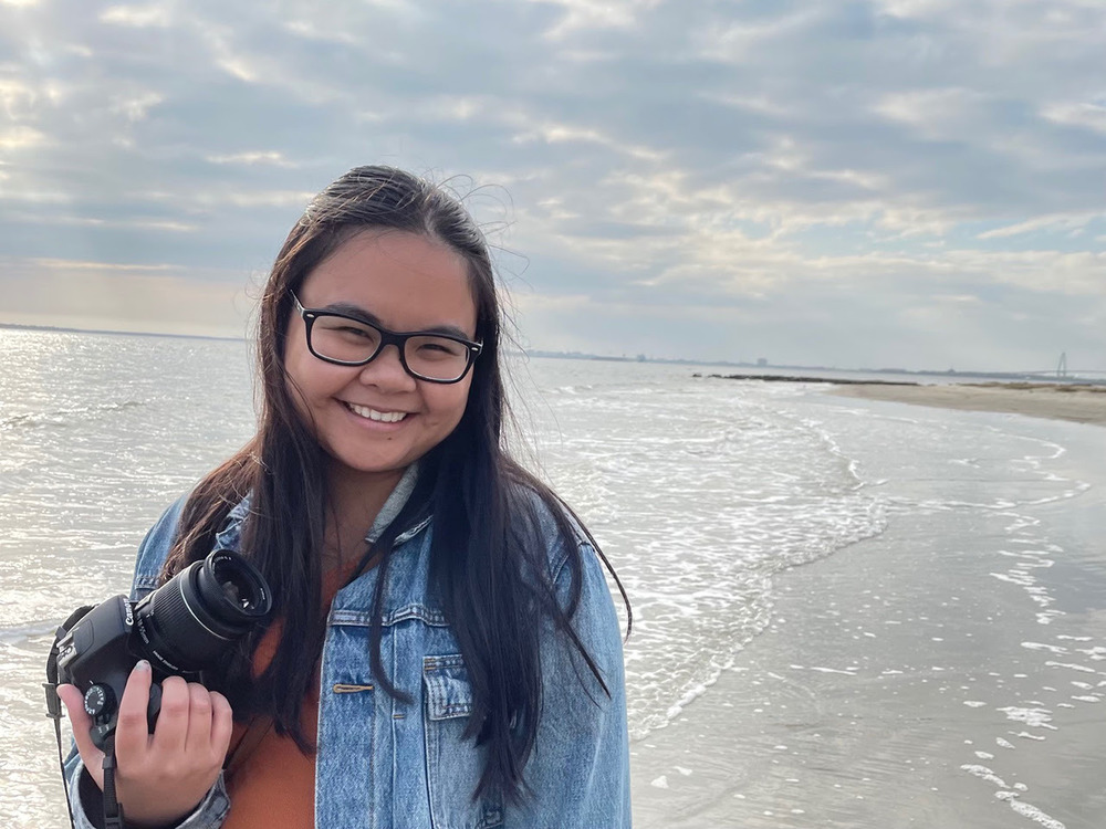 girl stand on the beach with camera in her hand