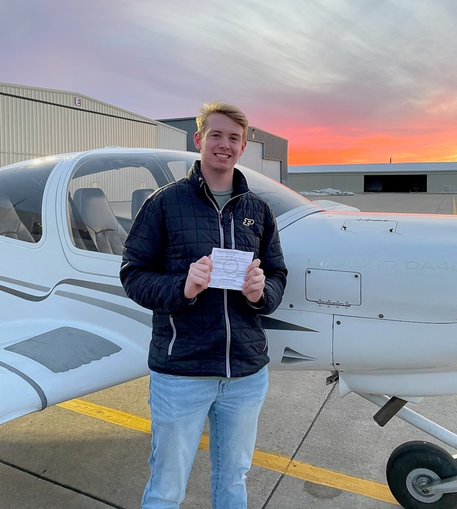 man standing by a airplane holding a certificate 