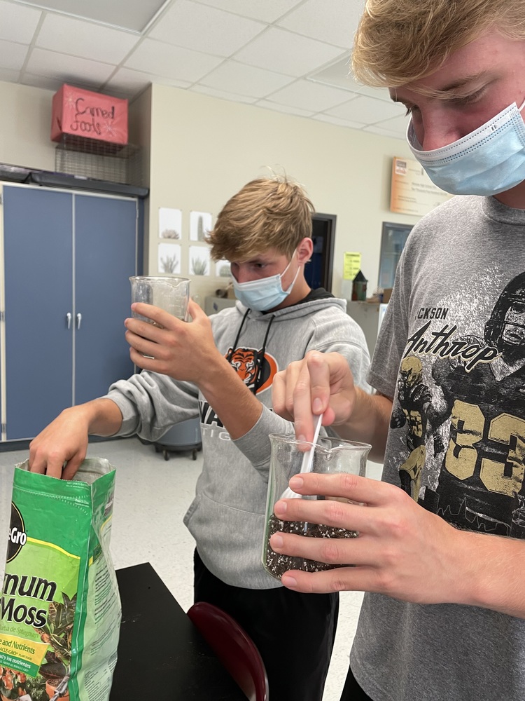 2 students filling cups with dirt