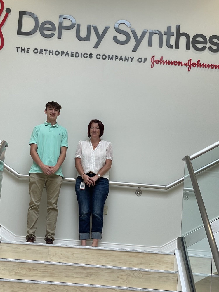 student & adult standing in front of DePuy sign